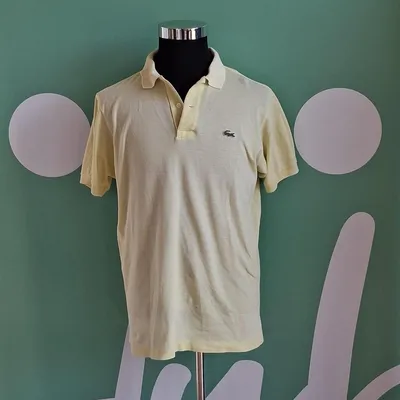 Tshirt polo di colore giallo pastello, taglia non specificata ma probabilmente una XL/L, marca Lacoste